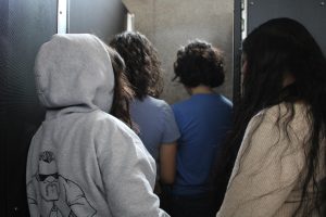 A simulated photo taken Mar. 12 of multiple students all in one M restroom stall, violating the rule of the sign applied on the door. 
