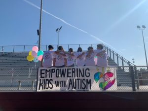 Ings' friends gather next to the “Empowering Kids with Autism” sign at the walk-a-thon to show support. “During the event a lot of my friends came and helped out as well,” Ing said. 