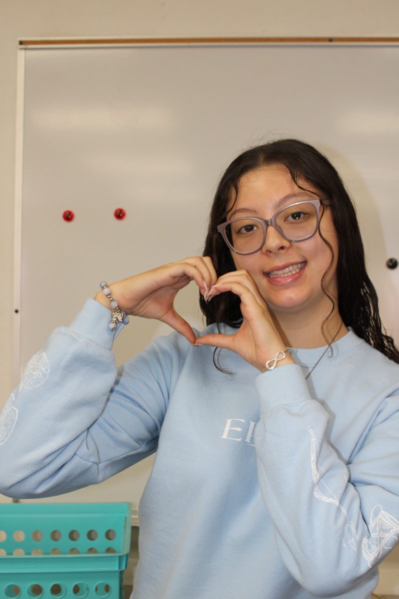 Raylene Guadron stands in front of the whiteboard, playfully raising her hand to put up a heart.  The pose reflects the joy and pride she gained for her program through her four years of dedication to her yearbook staff. “I feel really honored that it's written about me and especially about my journey in yearbook, since yearbook has done so much for me. I feel really honored,” said Guadron. Photo by Luna Medina.