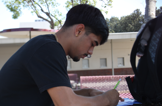 Junior and wrestler Elias Huerta does chemistry homework in the quad before wrestling practice. Huerta had to balance wrestling, homework, and social life. ¨I had all this homework to do and my grades started to drop, but I stuck with it because I didn't want to go home and say I quit,” Huerta said. Photo by Carmen Argueta
