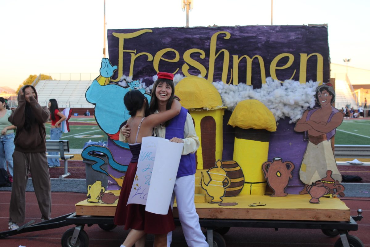 Freshmen Rio Che and Gabriella Medina hug in their skit as Jasmine and Aladdin on the track on Oct. 17.