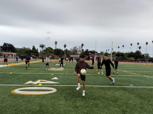 The boys’ soccer team practices in the rain for their first game of the season. 2-3 players per team kicks the ball around as a form of practice. This team includes (left to right) junior Aaron Christof Navalta and junior Sebastian Quezada.