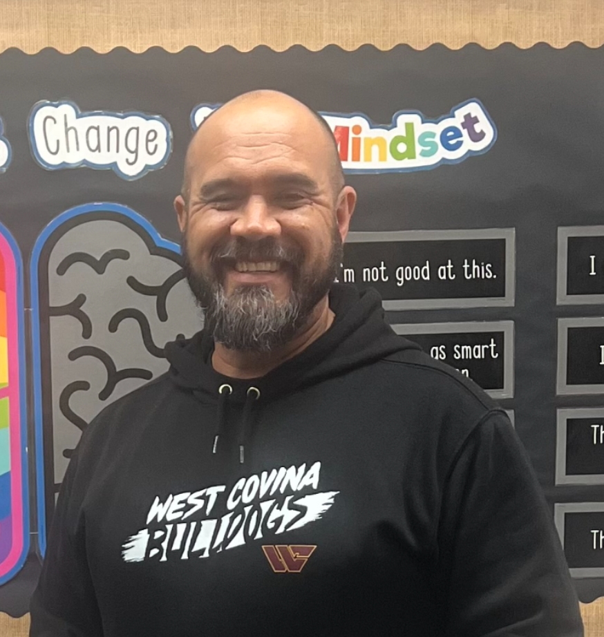 Aaron Schumacher in front of a banner that depicts the differences between “fixed” and “changed” mindsets for his students that reflects his ideal method of teaching.