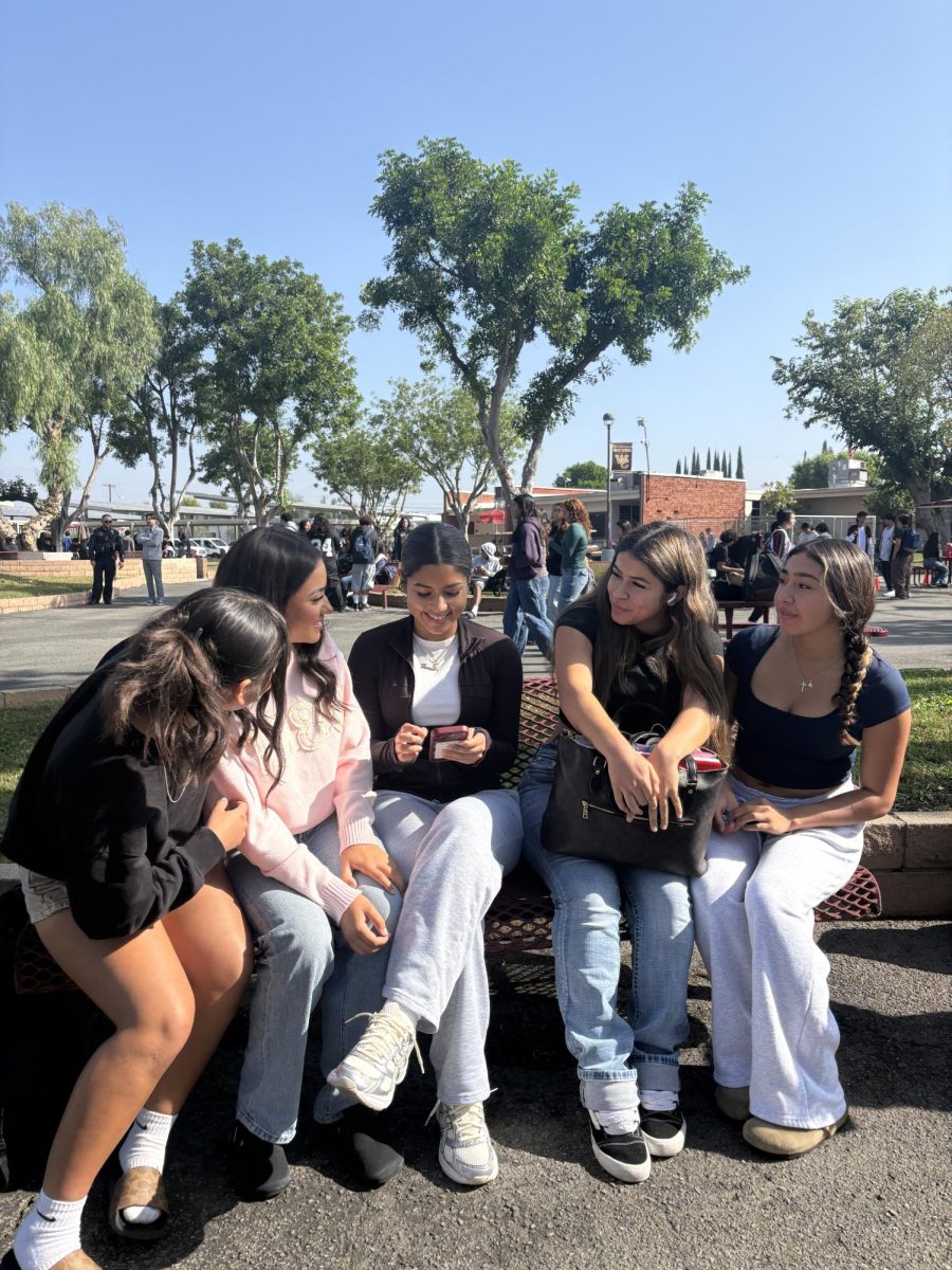 Left to right:  Freshman Zaylee Requena, Senior Jadyn Manriquez, Junior Isabella Solis, Sophomores Angelina Solis and Aubrey Maldonado talk to each other as Solis focuses on her phone to get all of her content posted on TikTok. “The reason why I keep posting is so I can make the money that I make from Tiktok, because when I review the clothing, I get commission off of it, so that's why I keep posting,” Solis said. 